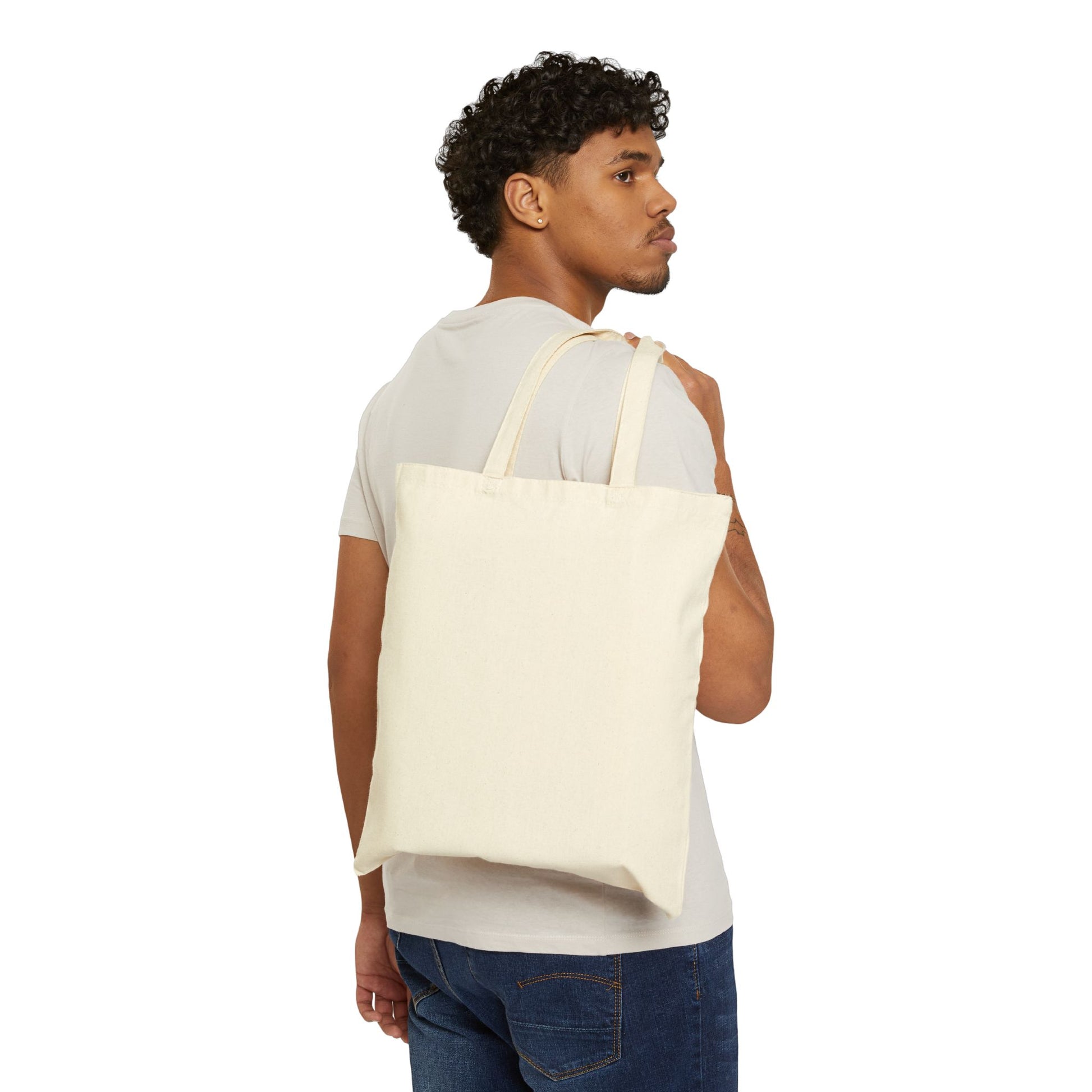 Man carrying a plain cream canvas Revolutionary by Nature tote bag over shoulder by Printify