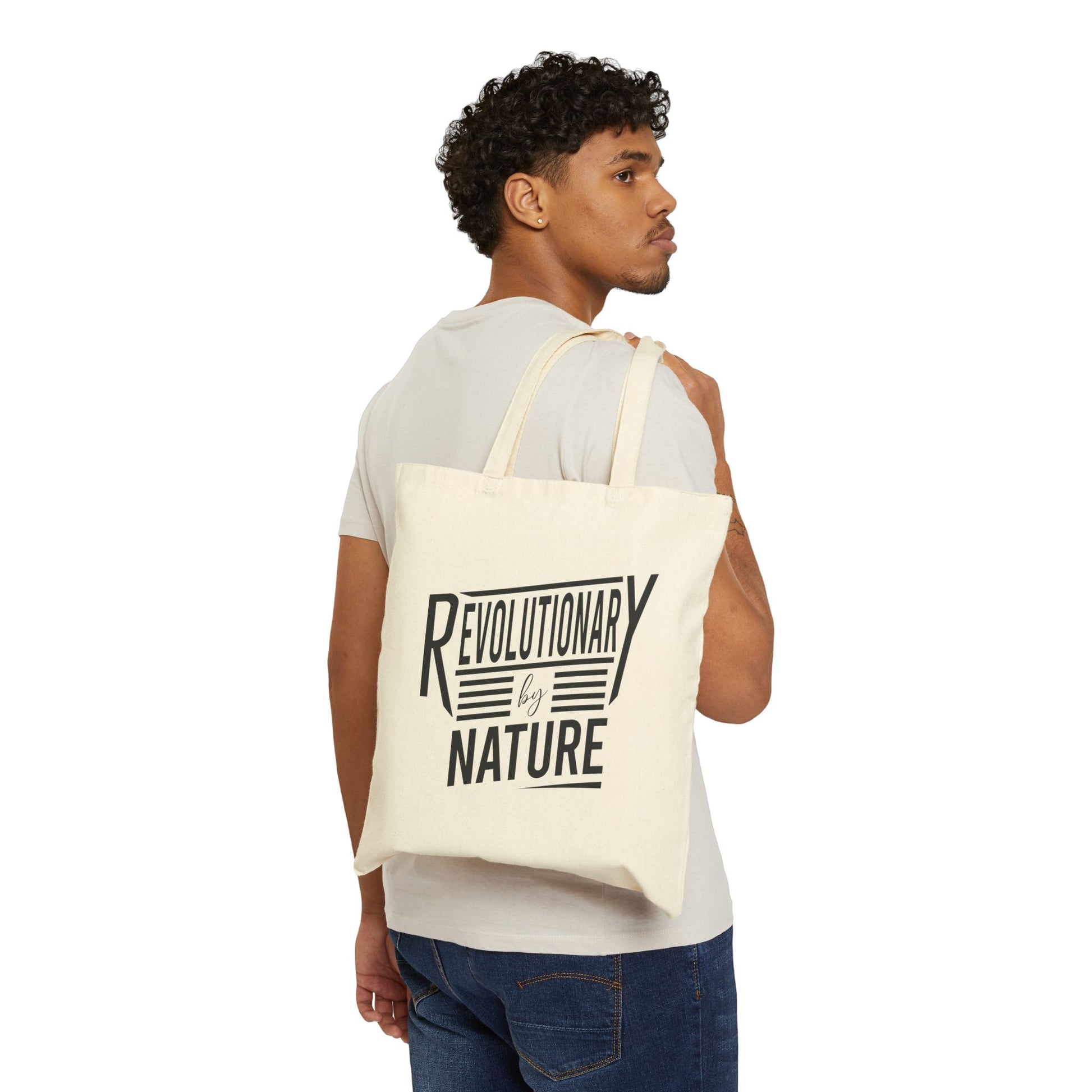 Man wearing a Revolutionary by Nature tote bag by Printify in beige canvas with black text design